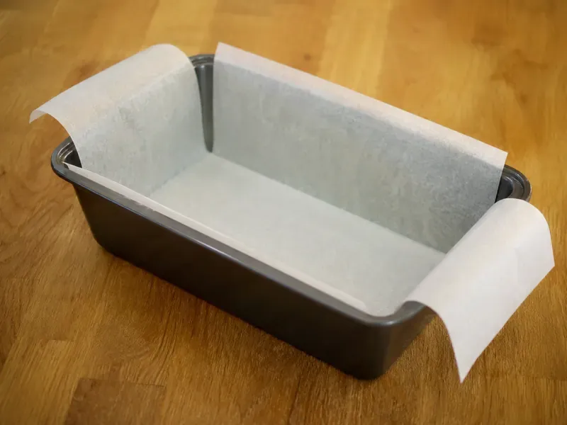 Loaf pan greased and lined with parchment paper for banana bread.