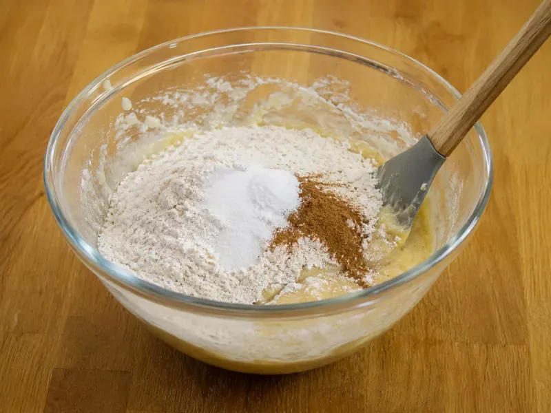Dry ingredients folded into banana yogurt batter with a spatula.