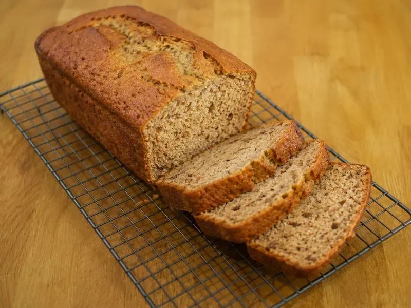 Finished banana bread with yogurt cooling and sliced to show the moist crumb.
