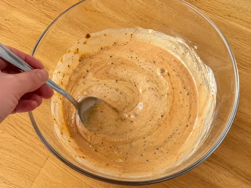 Ranch dressing and BBQ sauce mixed in a bowl to make creamy BBQ ranch dressing.