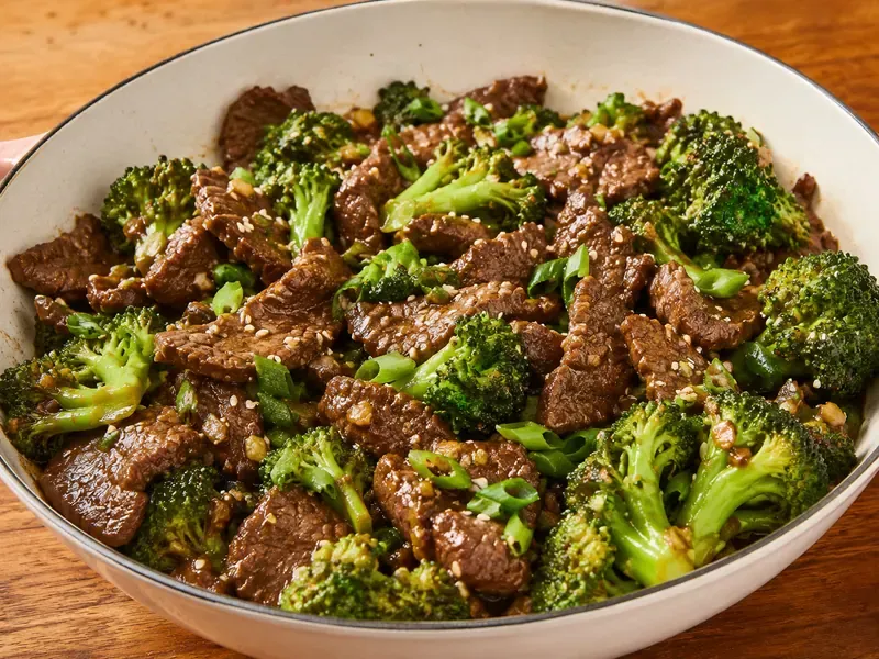 Beef and broccoli skillet with tender sliced beef, bright broccoli, green onions, sesame seeds, and savory sauce.