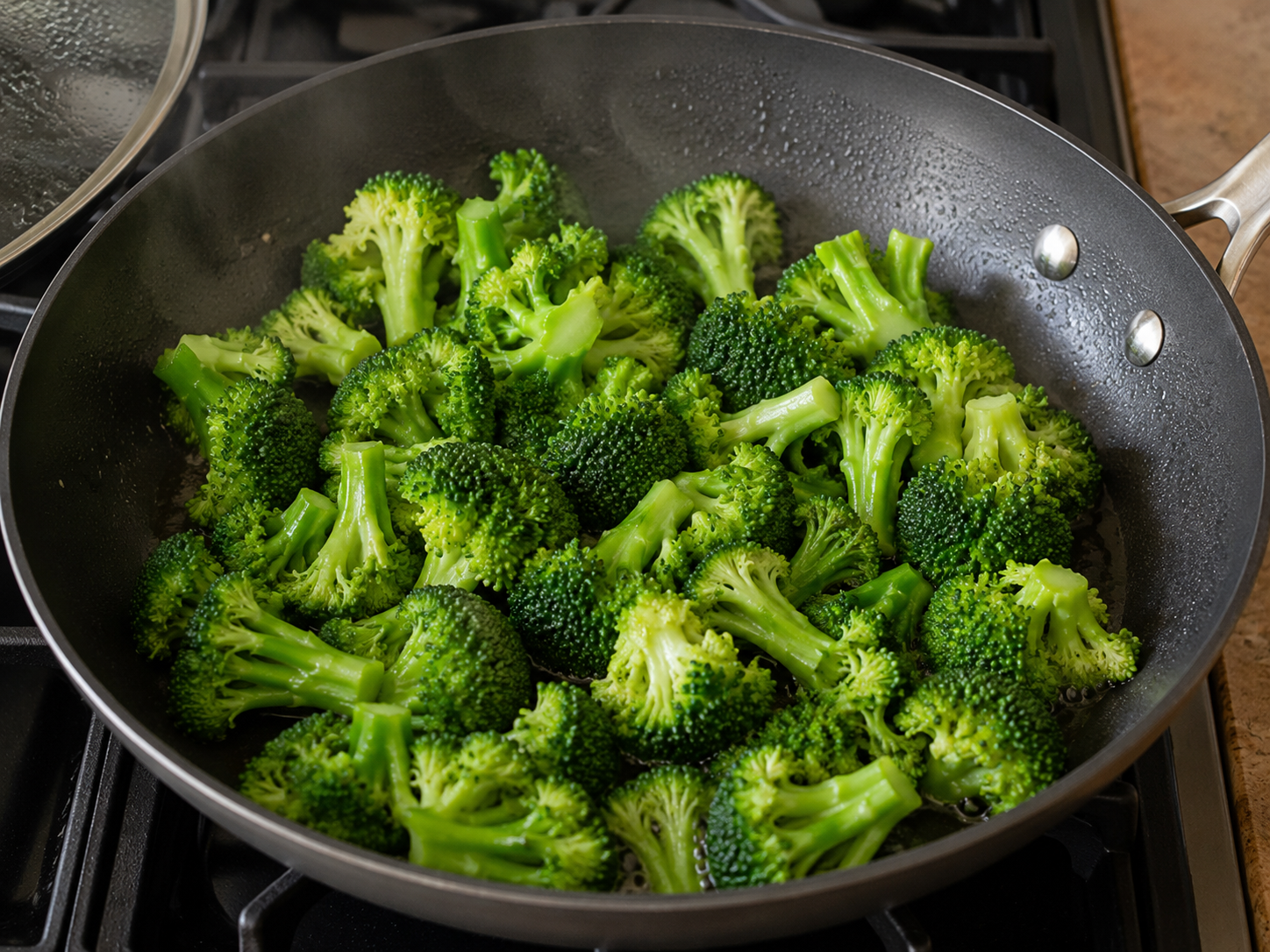 Broccoli florets cooking in a skillet until bright green and crisp-tender.