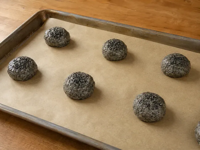 Black sesame cookie dough scooped onto a baking sheet.