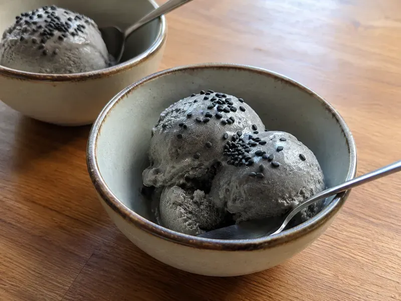 Finished black sesame ice cream scooped into bowls with sesame seeds.