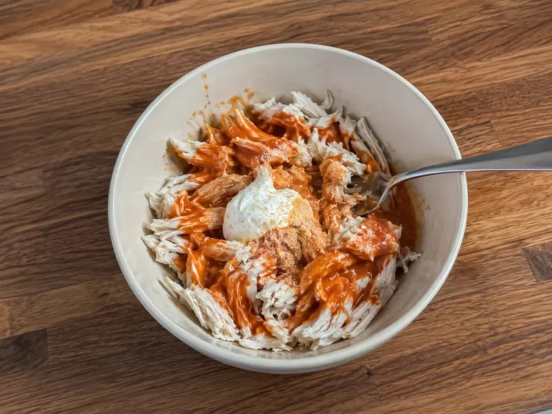 Shredded chicken mixed with buffalo sauce for buffalo chicken cottage cheese bowls.