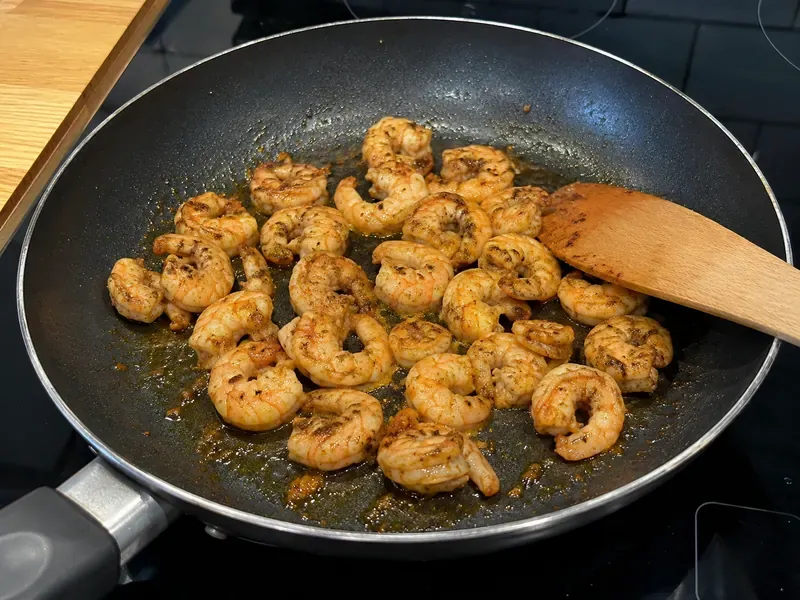 Cajun shrimp cooking in a skillet until pink and lightly browned.