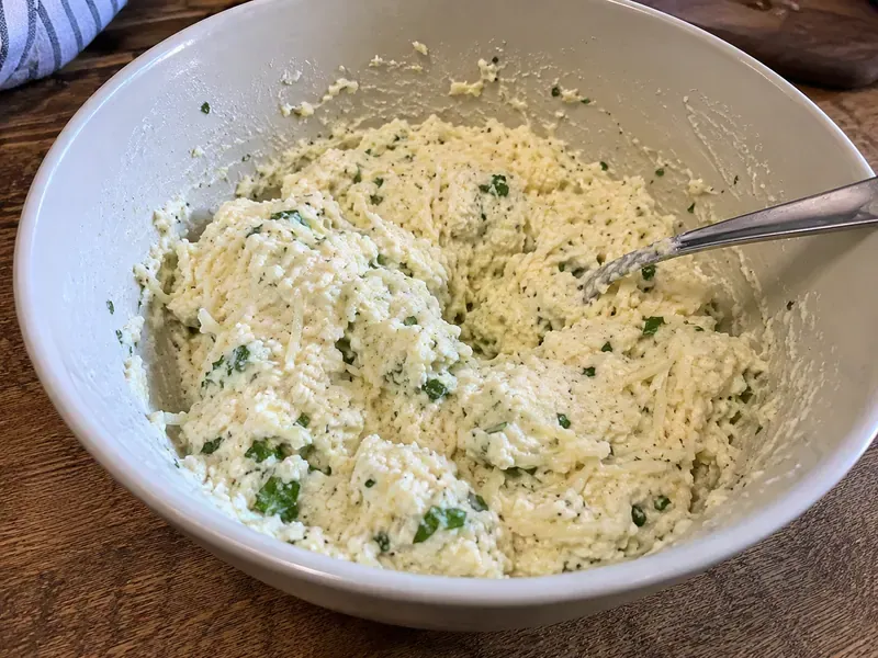 Ricotta, mozzarella, Parmesan, egg, and parsley mixed in a bowl for baked ziti cheese filling.