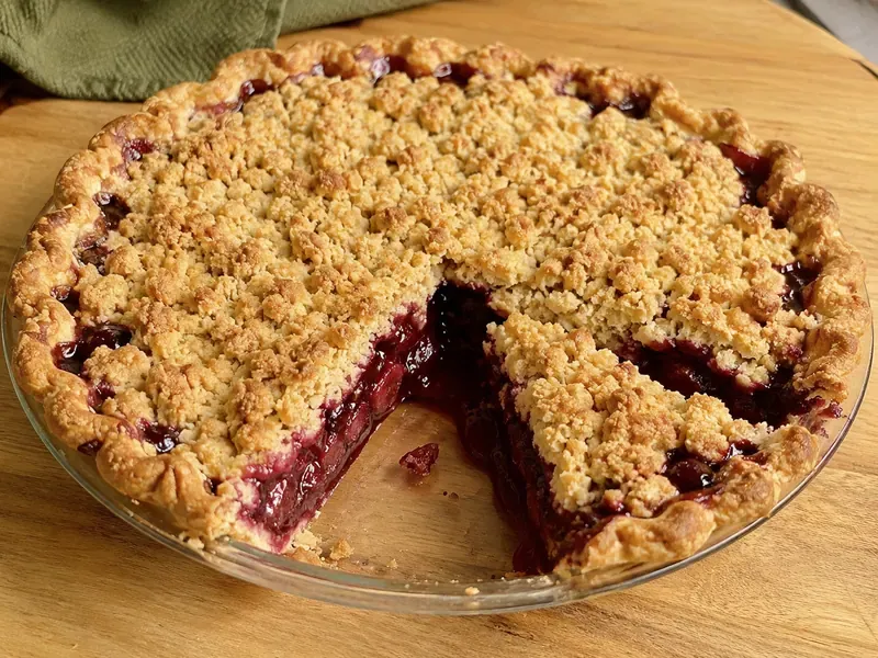 Finished cherry crumble pie sliced to show juicy filling and crumb topping.