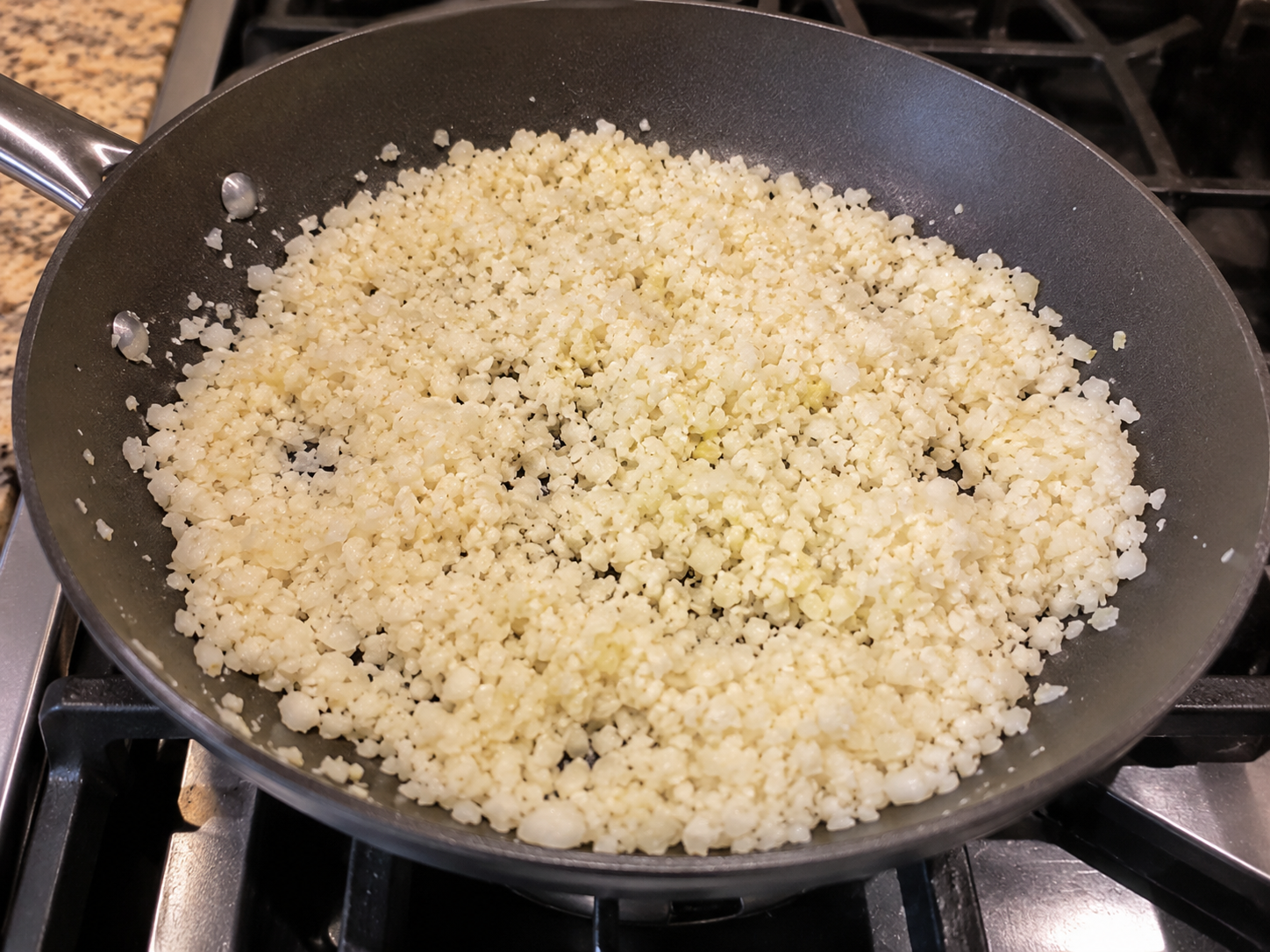 Cauliflower rice warming in a skillet.