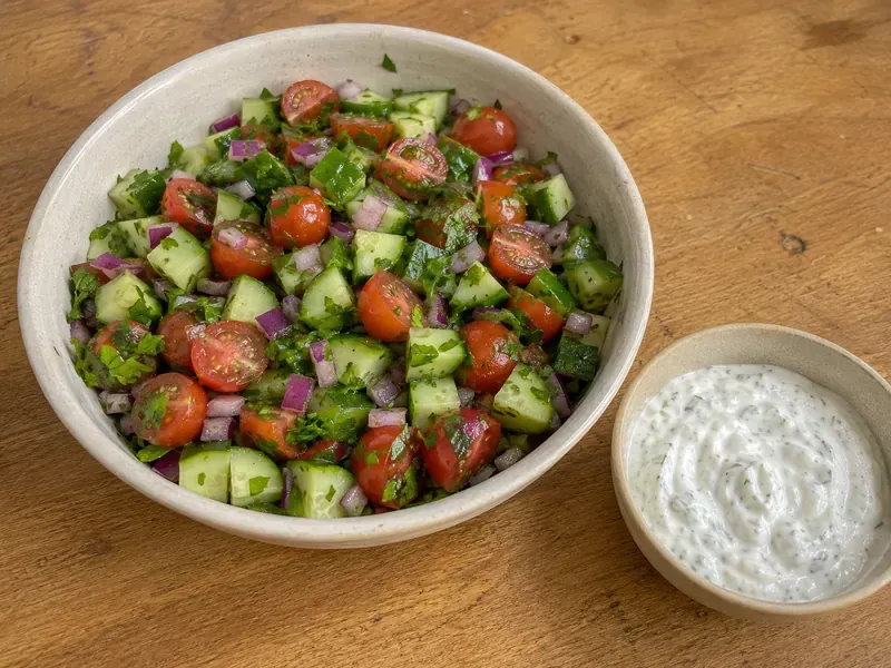 Cucumber tomato salad and garlic yogurt sauce prepared for chicken shawarma protein bowls.