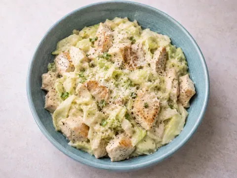 Creamy cabbage Alfredo with chicken in a skillet or bowl with creamy sauce, parmesan, garlic, and parsley.