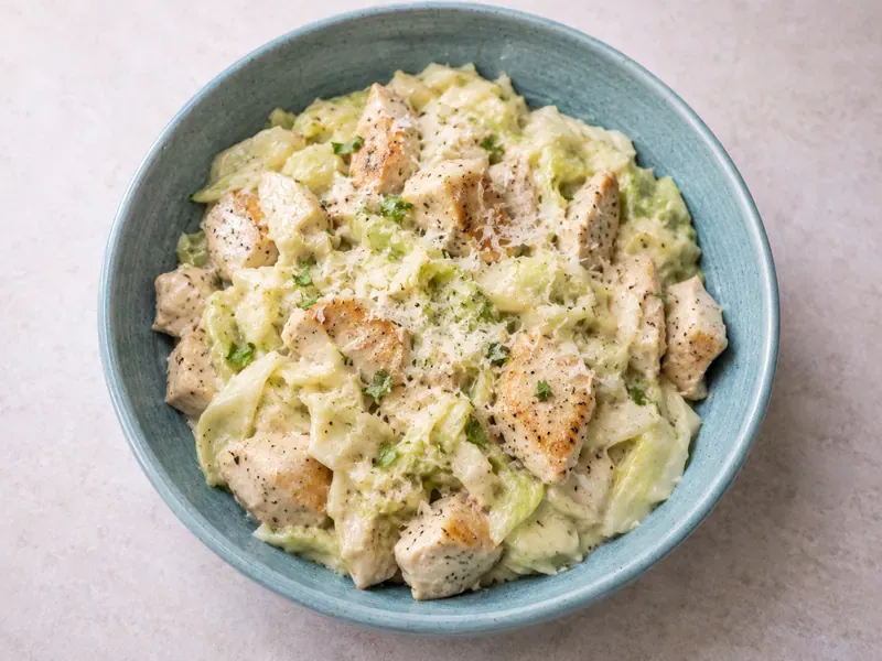 Creamy cabbage Alfredo with chicken in a skillet or bowl with creamy sauce, parmesan, garlic, and parsley.
