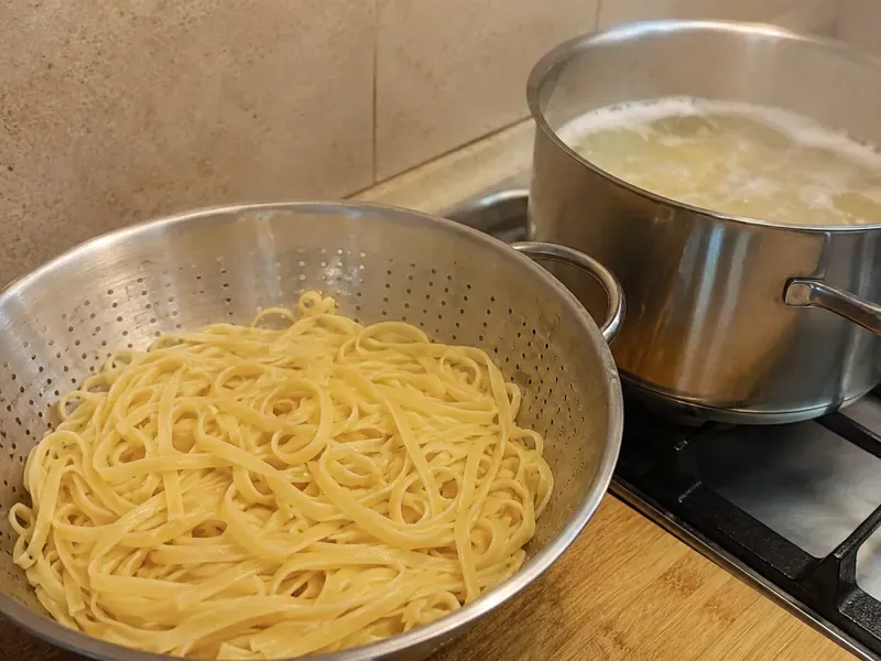 Pasta cooking in a pot of boiling water for creamy garlic chicken pasta.