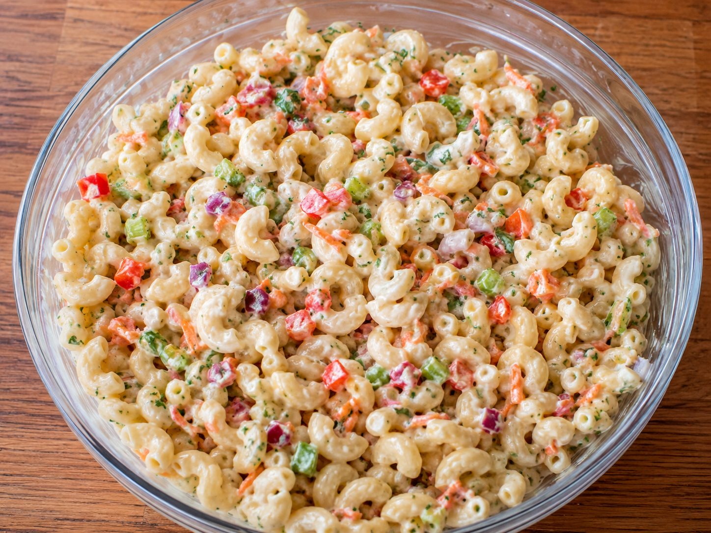 Creamy macaroni salad with elbow pasta, celery, red bell pepper, carrot, red onion, parsley, and creamy dressing.