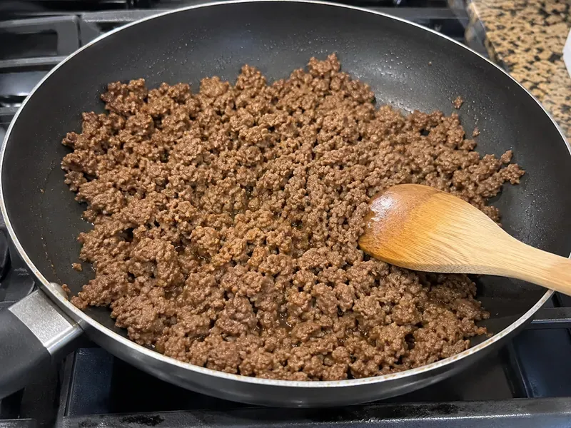 Lean ground beef cooking in a skillet for cabbage taco wraps.