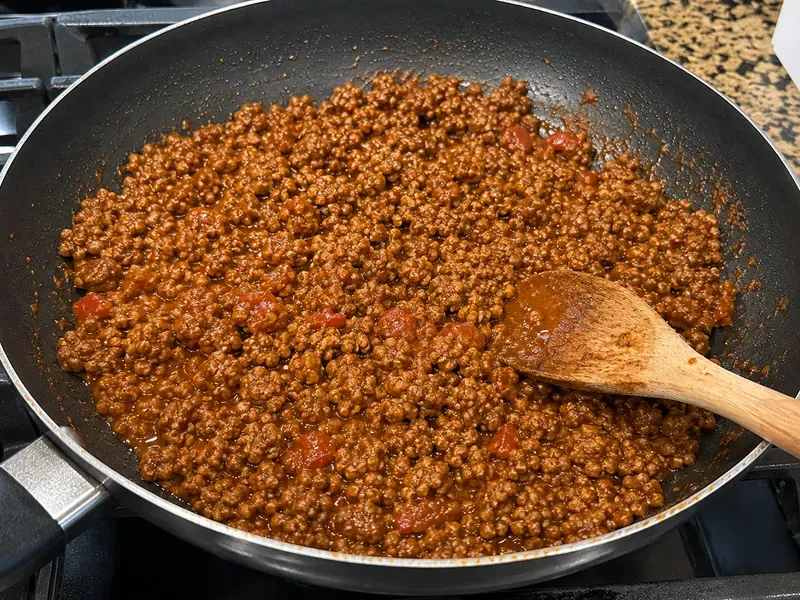 Ground beef seasoned with taco spices and salsa in a skillet.