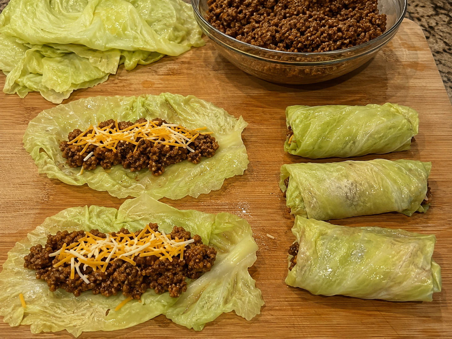 Softened cabbage leaves filled with taco beef and shredded cheese before folding.