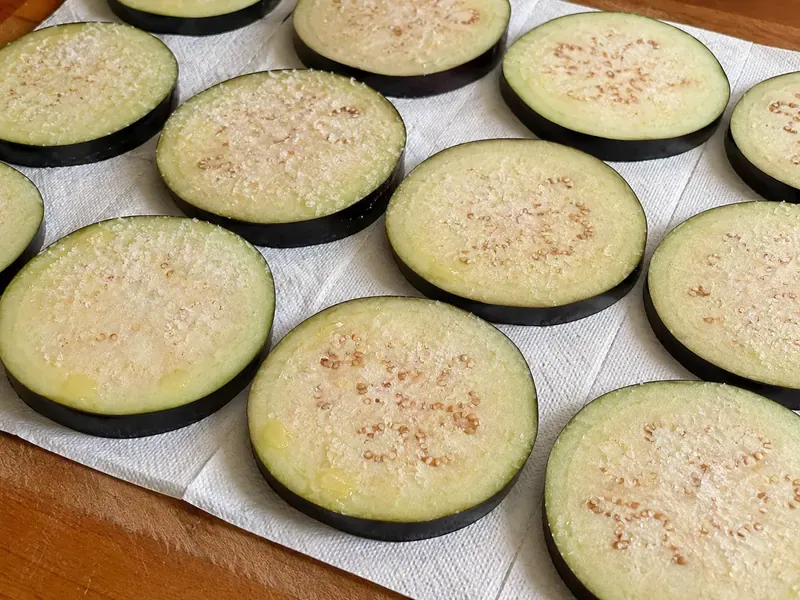 Eggplant rounds salted on paper towels before breading.