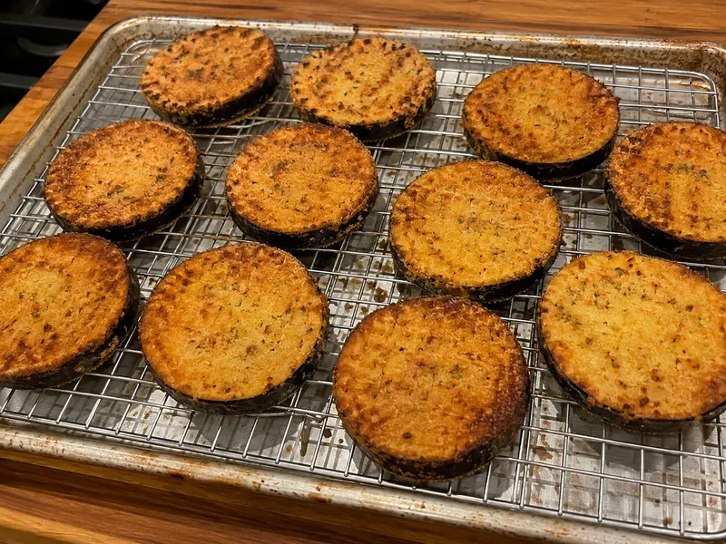 Breaded eggplant rounds baked until golden and crisp on a sheet pan.