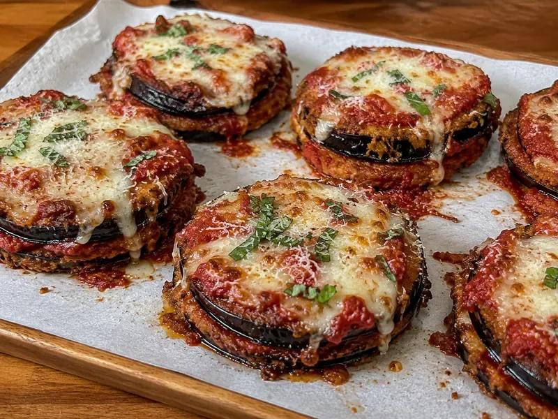 Finished Crispy Eggplant Parmesan Stacks with melted cheese, sauce, and basil.
