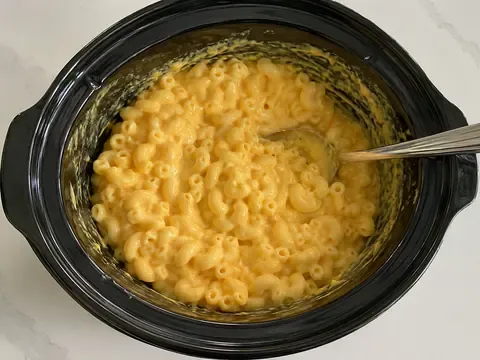Crock Pot Recipe for Macaroni and Cheese with Velveeta final image showing creamy crock pot macaroni and cheese with Velveeta, smooth melted cheese sauce, elbow macaroni, a serving spoon, and a practical potluck slow cooker setup.
