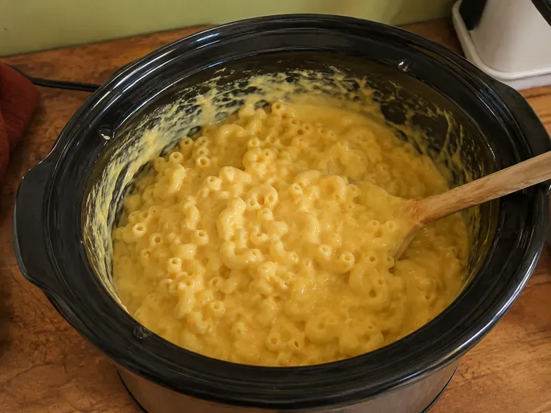 Crock pot macaroni and cheese cooking until cheese melts into a creamy sauce.