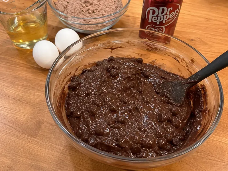 Brownie mix stirred with Dr Pepper, oil, and eggs in a mixing bowl.