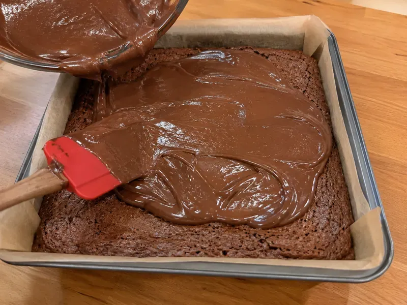 Warm chocolate glaze spread over baked Dr Pepper brownies.