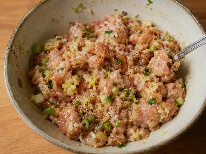 Ground chicken filling mixed with garlic, ginger, green onions, soy sauce, sesame oil, and rice vinegar.
