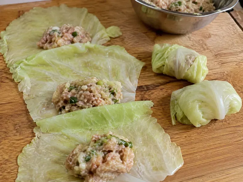 Softened cabbage leaves filled with chicken mixture and folded into dumpling packets.