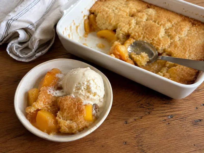 Warm peach cobbler served with a scoop of vanilla ice cream.