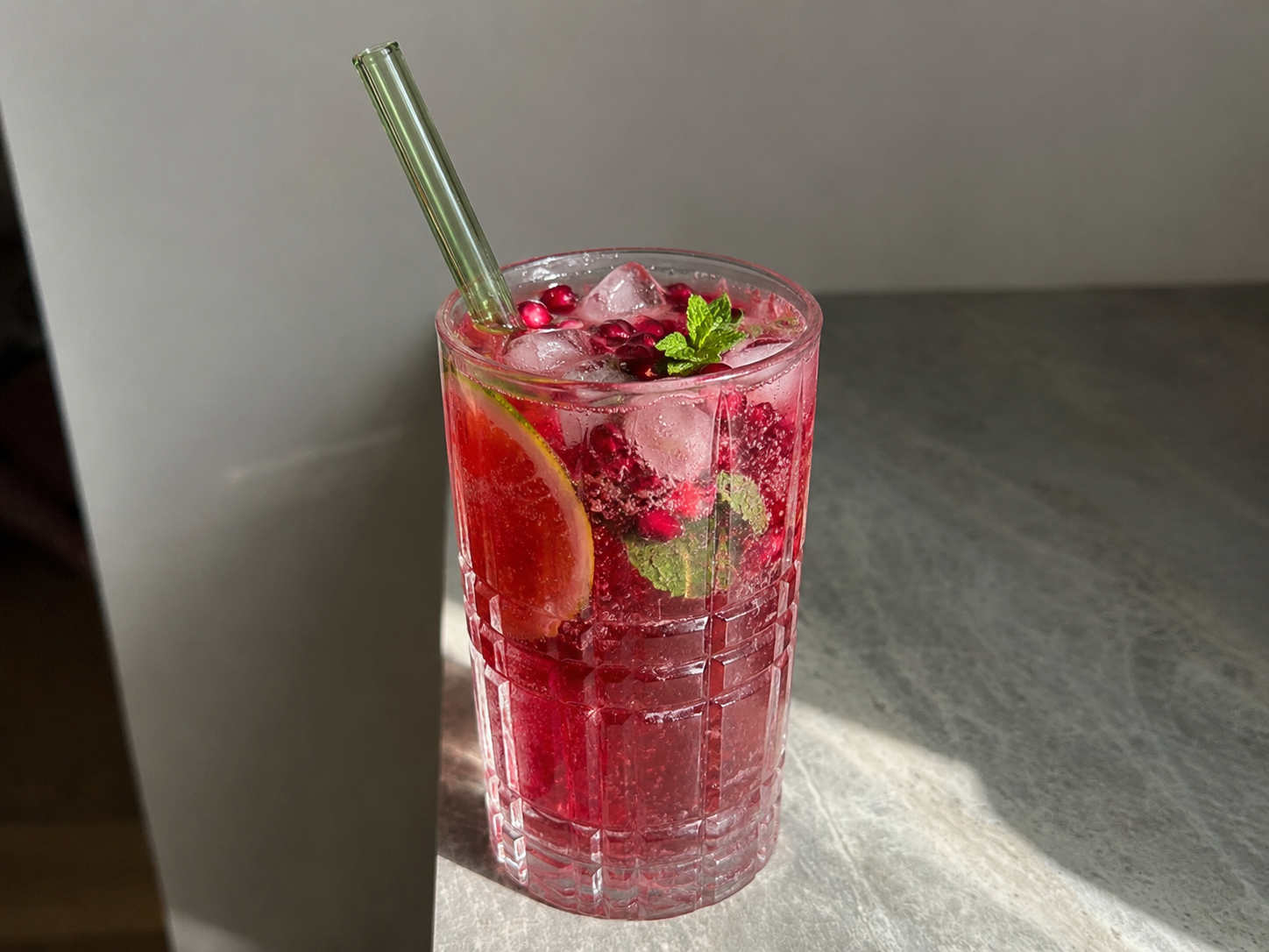 Easy Pomegranate Spritz Mocktail with ruby-red juice, ice, citrus, mint, bubbles, and pomegranate arils.