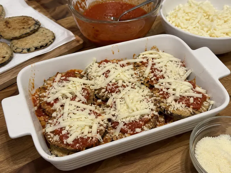 Crispy eggplant layered with marinara, mozzarella, and parmesan in a baking dish.