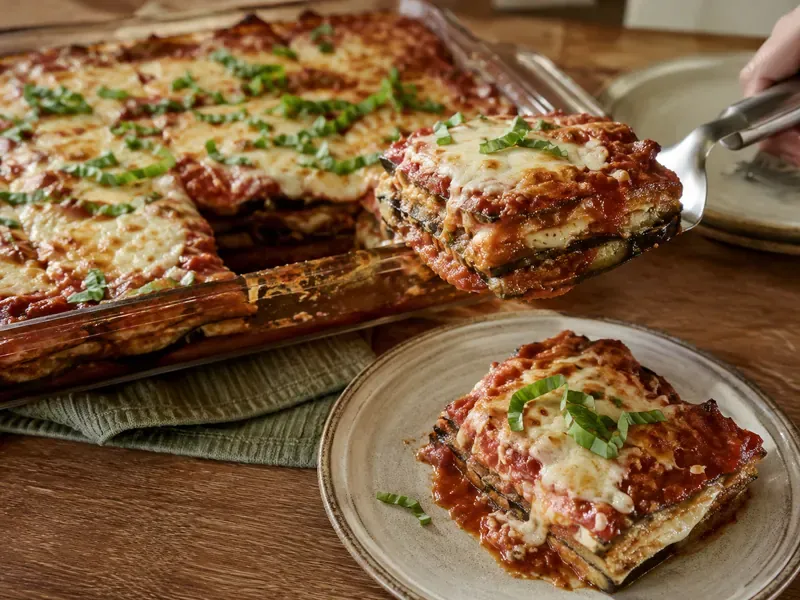 Finished eggplant parmesan sliced with melted cheese, marinara, and basil.