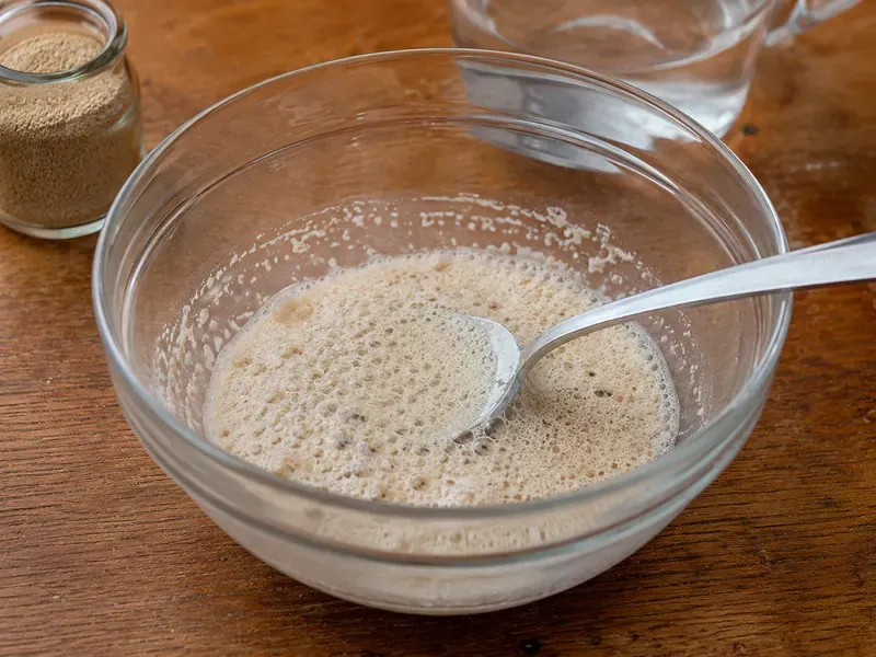 Yeast, warm water, and honey foaming in a bowl.
