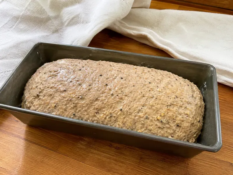 Ezekiel bread dough rising in a greased loaf pan.