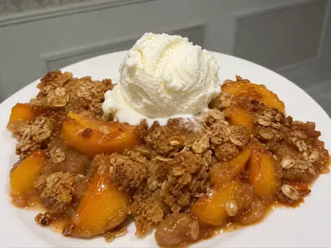 Fresh Peach Crisp with juicy baked peaches, golden oat crumble, and vanilla ice cream.