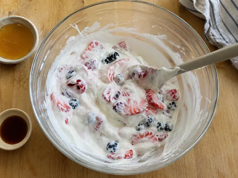 Berries mixed with greek yogurt, honey, and vanilla in a bowl.