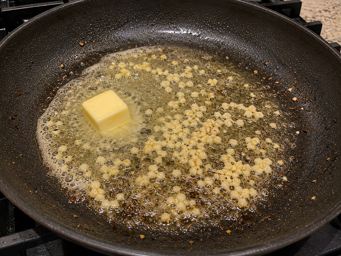 Butter melting in a skillet with minced garlic to make garlic butter sauce.