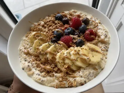Greek yogurt banana protein bowl with oats, peanut butter, chia seeds, banana slices, and optional berries.