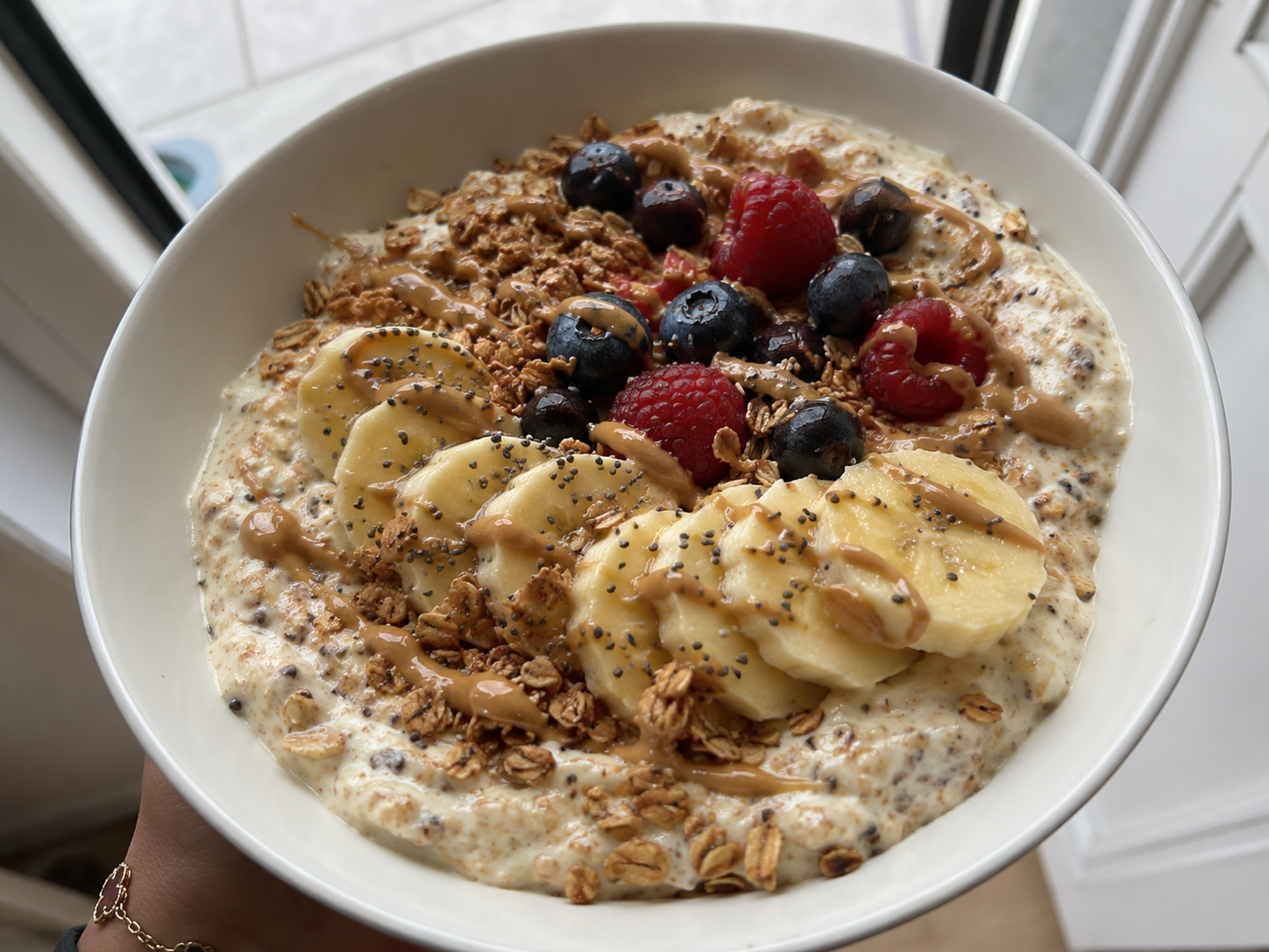 Greek yogurt banana protein bowl with oats, peanut butter, chia seeds, banana slices, and optional berries.