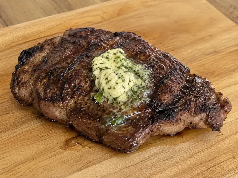 Freshly grilled steak resting with garlic herb butter melting on top.