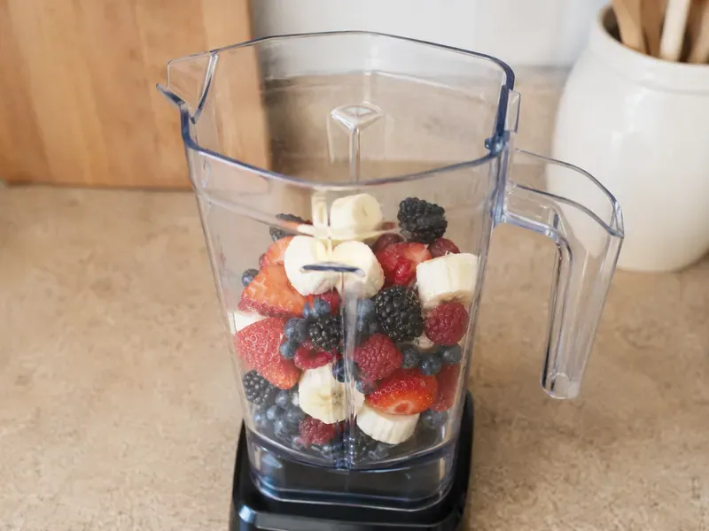 Mixed berries and banana added to a blender jar.