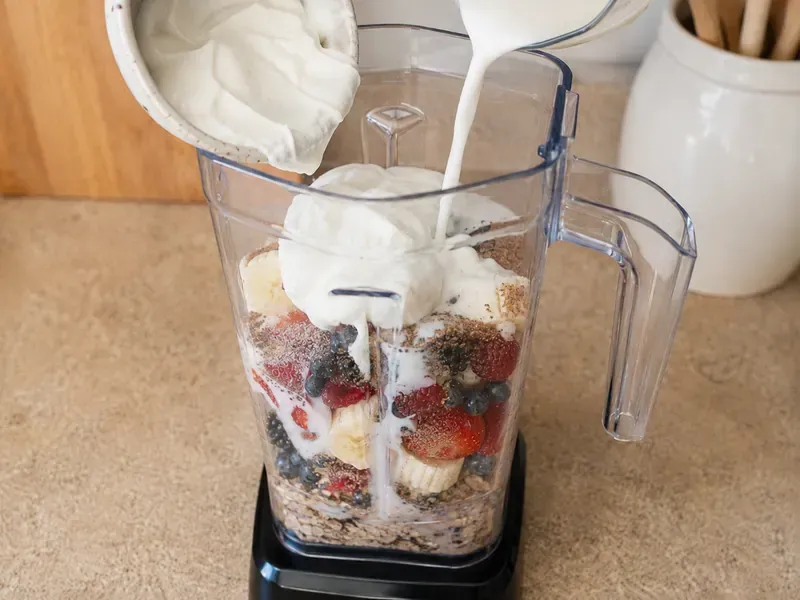 Oats, chia seeds, and ground flaxseed added over berries in the blender.