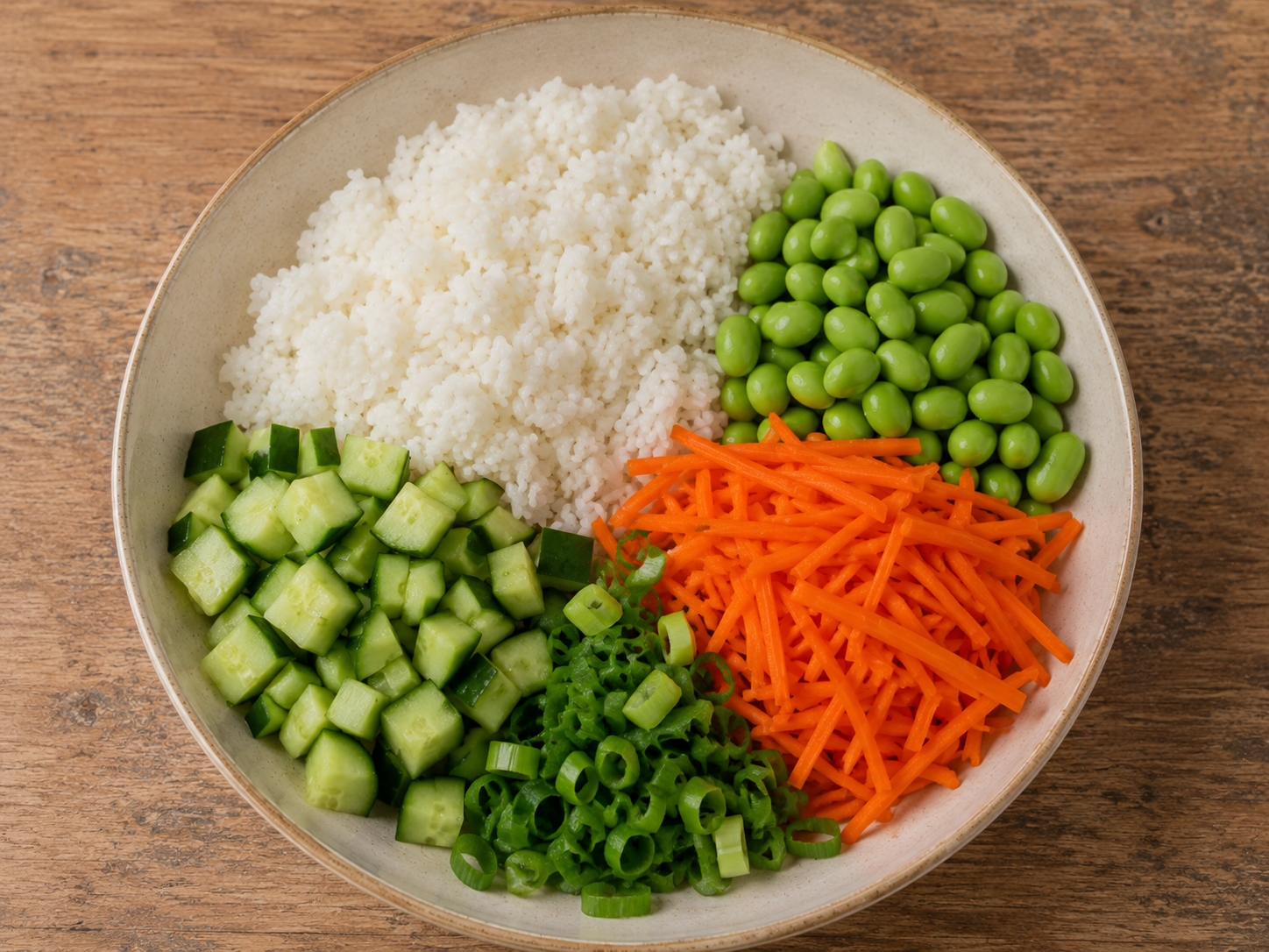 Rice, edamame, cucumber, carrots, and green onions prepared for a chicken rice bowl.
