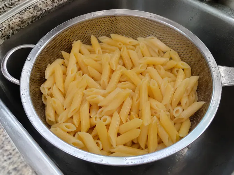 High-protein pasta cooking in a pot or draining in a colander.