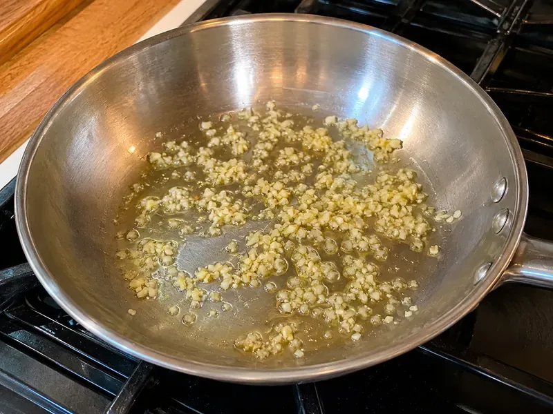 Minced garlic cooking gently in olive oil in a skillet.