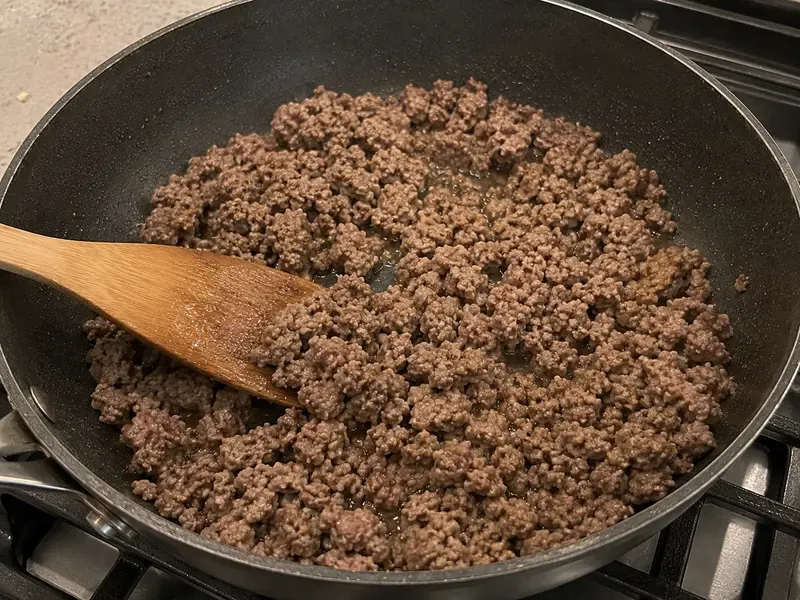 Lean ground beef cooking in a skillet for high protein Turkish pasta.