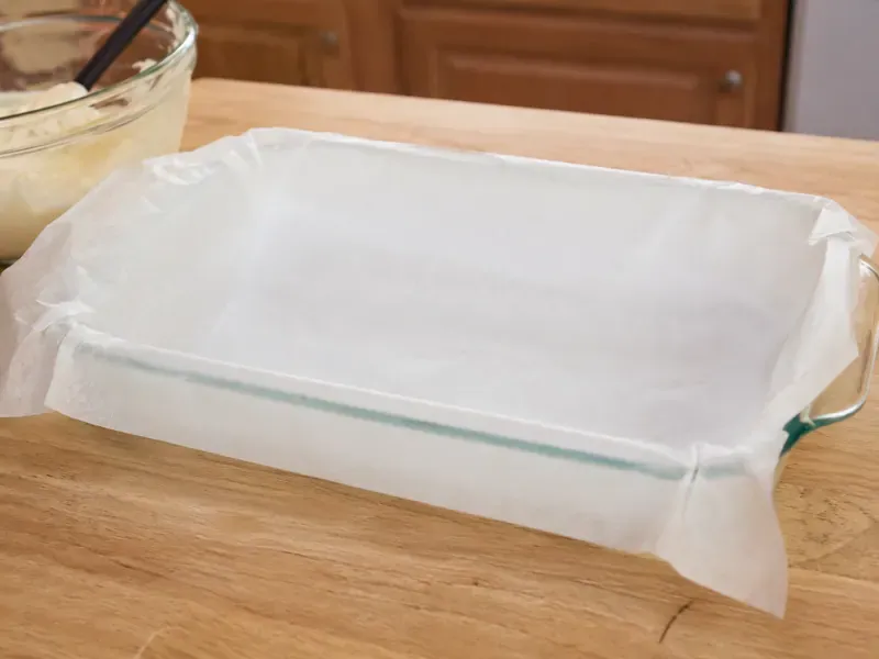 Lined 9x13-inch baking dish prepared for ice cream sandwich dessert.