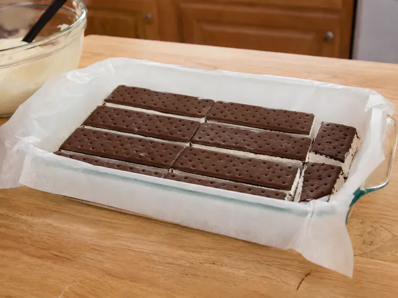 Ice cream sandwiches arranged in the bottom of a lined baking dish.